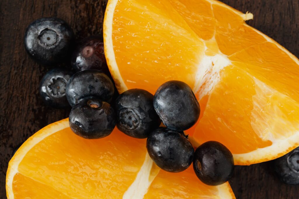 closeup of delicious blueberries placed on juicy oranges on wooden table